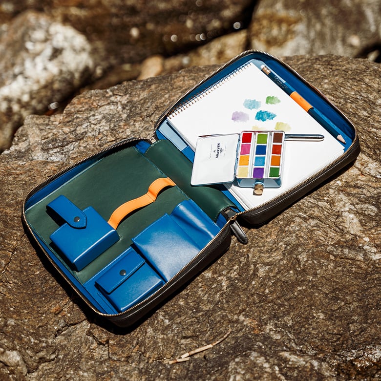 L’Artist Folio Smythson ouvert avec son coffret d’aquarelles, son pinceau et son crayon